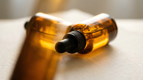 Amber dropper bottle of firming serum in a warm golden glow.